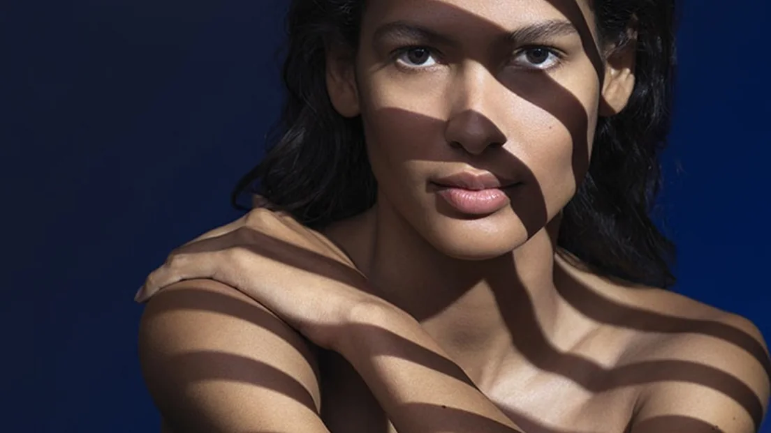 Imagem de campanha do protetor solar facial Anthelios UVMune 400 FPS60, com rosto exposto à luz e sombras