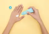 Aplicação de creme nas mãos com bisnaga e creme visível