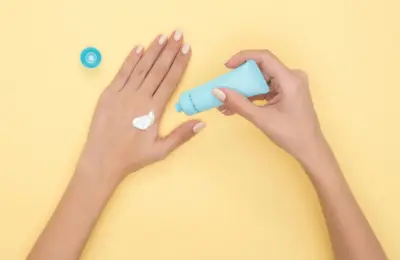 Aplicação de creme nas mãos com bisnaga e creme visível