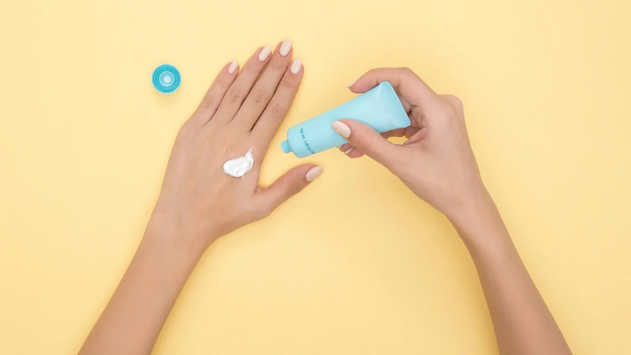 Aplicação de creme nas mãos com bisnaga e creme visível