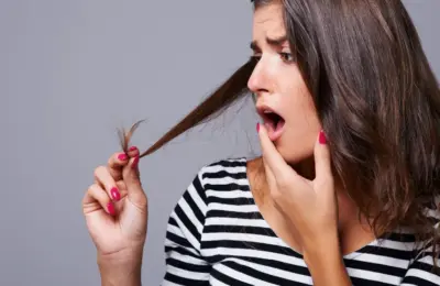 Pessoa observando uma ponta do cabelo em imagem ilustrativa sobre avaliação do estado dos fios