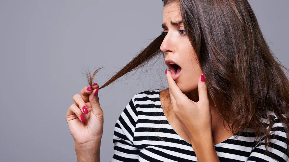 Pessoa observando uma ponta do cabelo em imagem ilustrativa sobre avaliação do estado dos fios