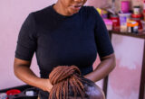 Pessoa com corte de cabelo curto em um salão, com produtos e ferramentas ao fundo