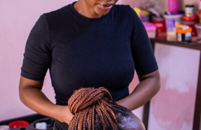 Pessoa com corte de cabelo curto em um salão, com produtos e ferramentas ao fundo