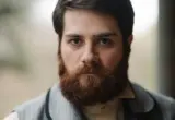 Homem com barba cheia e bem aparada em retrato ilustrativo