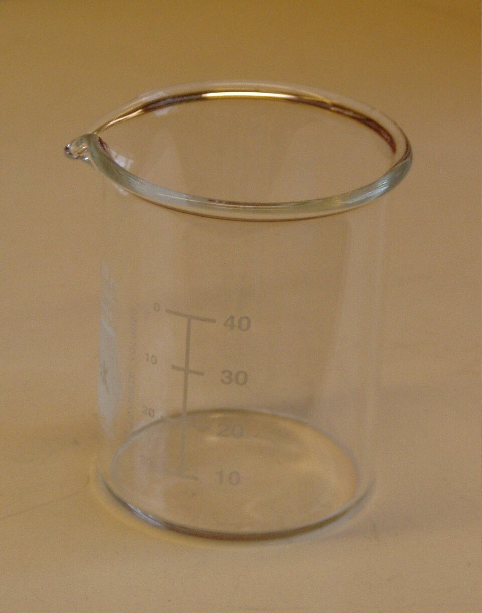 Béquer de vidro com marcações de volume usado como ilustração de ensaio de laboratório