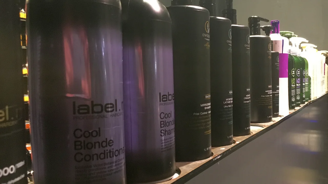 Fileira de frascos de shampoo e condicionador profissional em uma prateleira de salão