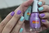 Mãos com unhas pintadas segurando dois frascos de esmalte em uma cena ilustrativa de manicure