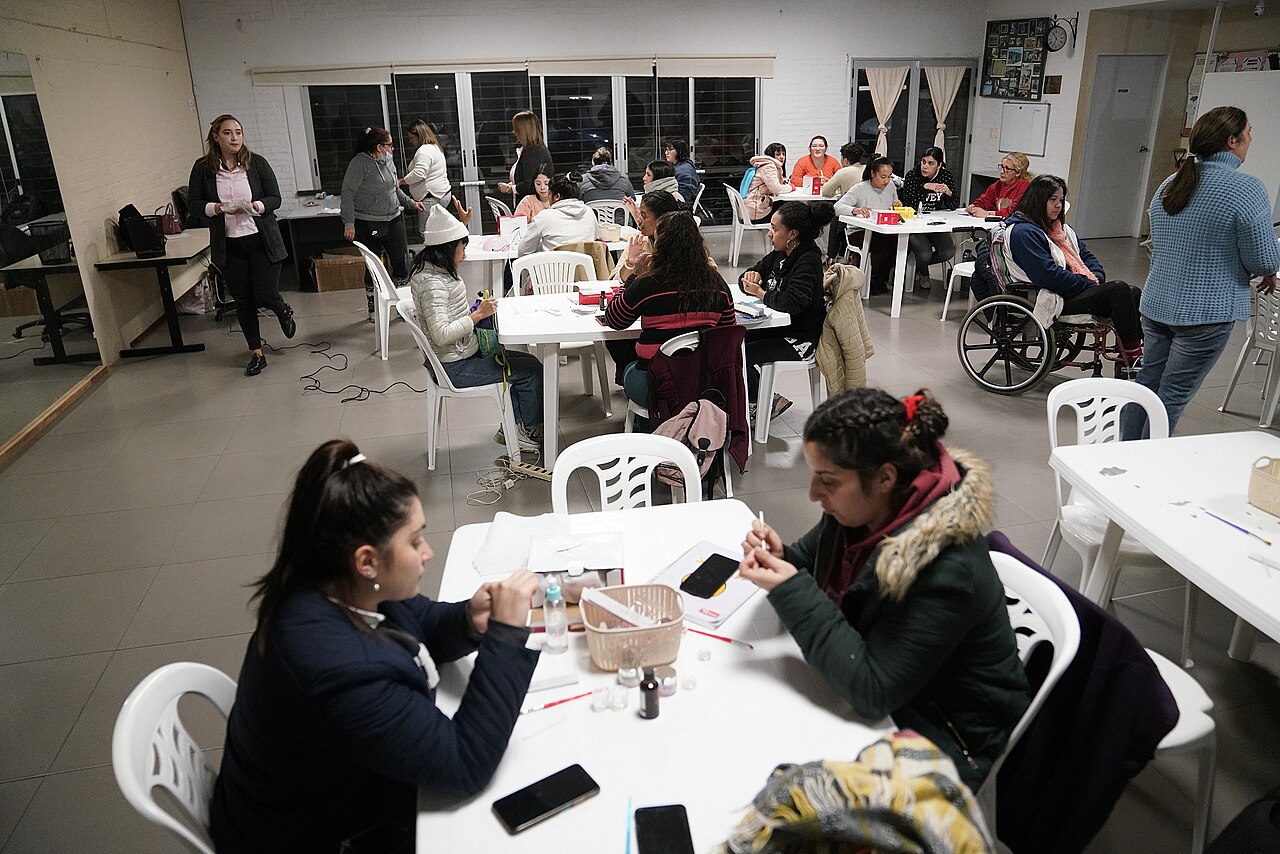 Turma reunida em capacitação prática de manicure, com profissionais treinando em mesas