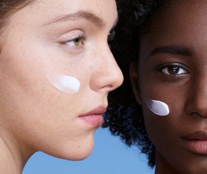 Duas pessoas com pequenas quantidades de produto no rosto em uma cena ilustrativa de cuidados faciais