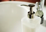 Frasco cosmético translúcido com válvula pump sobre uma pia, em foto ilustrativa
