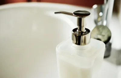 Frasco cosmético translúcido com válvula pump sobre uma pia, em foto ilustrativa