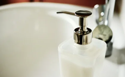 Frasco cosmético translúcido com válvula pump sobre uma pia, em foto ilustrativa
