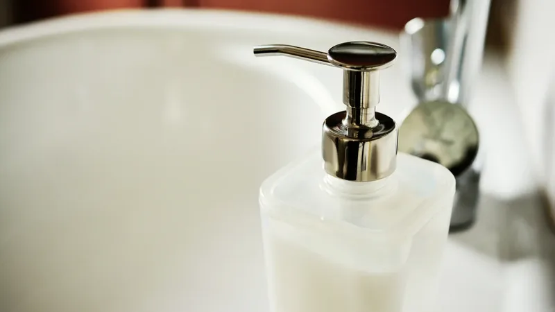 Frasco cosmético translúcido com válvula pump sobre uma pia, em foto ilustrativa