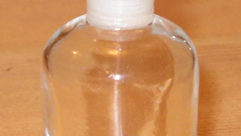 Detalhe de um pequeno frasco de perfume de vidro transparente com tampa rosqueável