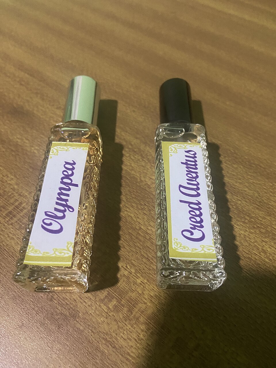 Dois frascos pequenos de perfume com formatos e tampas diferentes sobre uma superfície de madeira