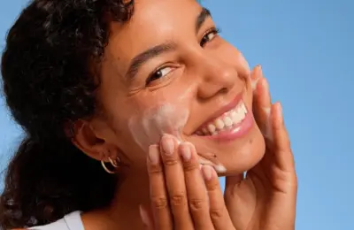 Pessoa aplicando produto de limpeza ou esfoliação facial com movimentos suaves no rosto.