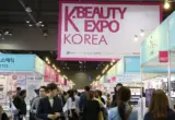Corredor de uma feira K-Beauty Expo Korea com estandes de marcas de beleza e visitantes
