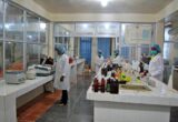 Profissionais trabalhando em laboratório de controle de qualidade com instrumentos e amostras