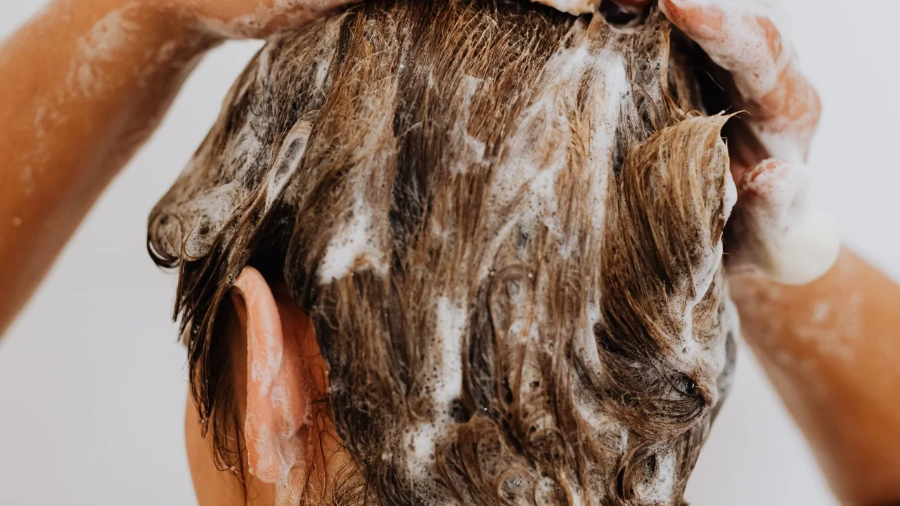 Cabelo sendo lavado com espuma de shampoo durante a higienização