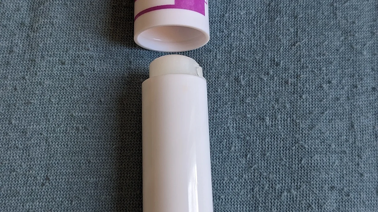 Produto de cuidado labial em bastão sobre tecido azul