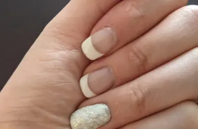 Unhas em manicure francesa com detalhe de brilho; imagem ilustrativa de cuidados com as unhas.
