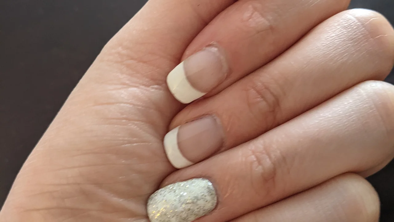 Unhas em manicure francesa com detalhe de brilho; imagem ilustrativa de cuidados com as unhas.