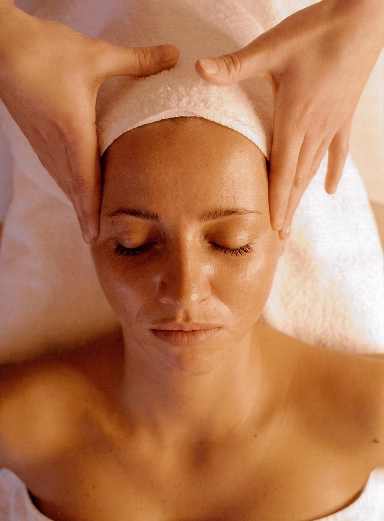 Atendimento de estética facial com manobras manuais na testa da cliente.