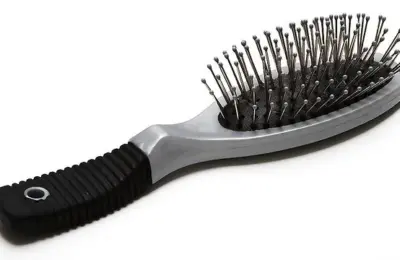 Escova de cabelo com almofada e pinos metálicos sobre fundo branco
