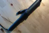 Modelador de cachos elétrico preto sobre uma mesa de madeira