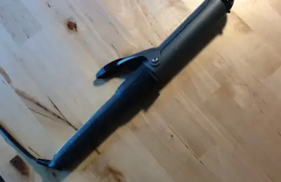 Modelador de cachos elétrico preto sobre uma mesa de madeira