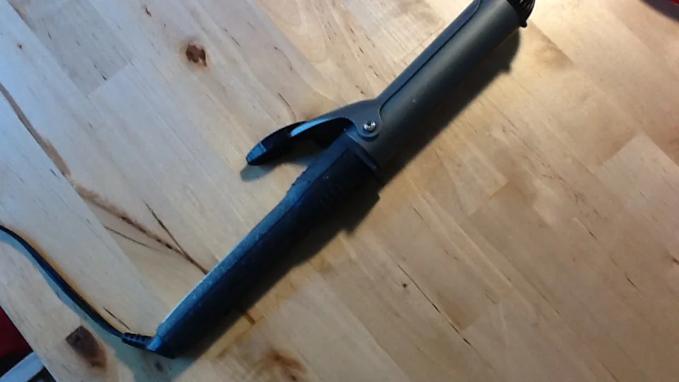 Modelador de cachos elétrico preto sobre uma mesa de madeira