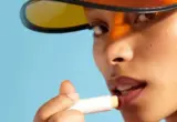 Imagem de pessoa aplicando produto labial em bastão, usada como exemplo visual de cuidado dos lábios.