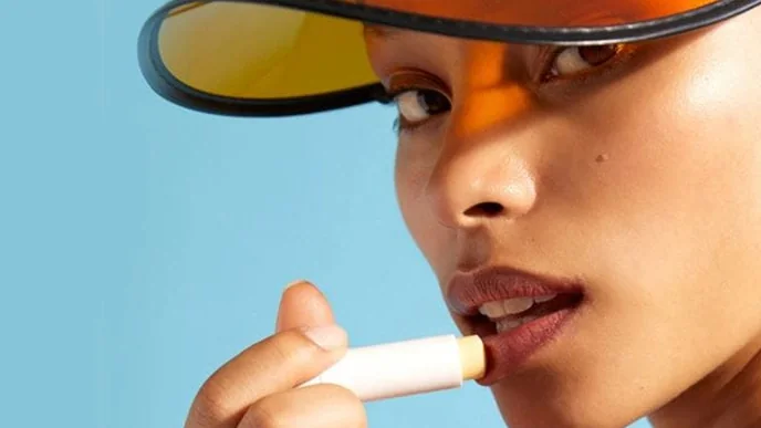 Imagem de pessoa aplicando produto labial em bastão, usada como exemplo visual de cuidado dos lábios