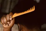 Pente de dentes largos sendo usado em cabelo crespo; imagem ilustrativa.