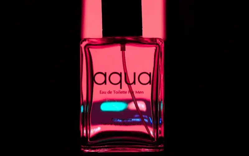 Frasco de fragrância masculina em composição com iluminação colorida, imagem ilustrativa