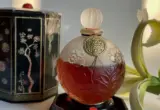 Frasco redondo do perfume A Suma, de Coty, em imagem ilustrativa sobre formatos de perfumaria