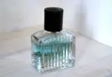 Frasco de perfume transparente com tampa preta sobre superfície clara, imagem ilustrativa