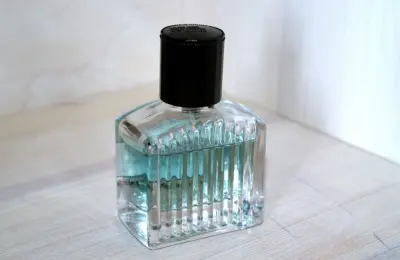 Frasco de perfume transparente com tampa preta sobre superfície clara, imagem ilustrativa
