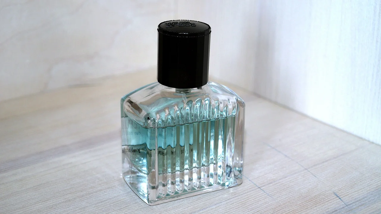 Frasco de perfume transparente com tampa preta sobre superfície clara, imagem ilustrativa