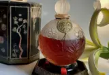 Garrafa vintage de perfume Suma ao lado da caixa decorada e de uma flor