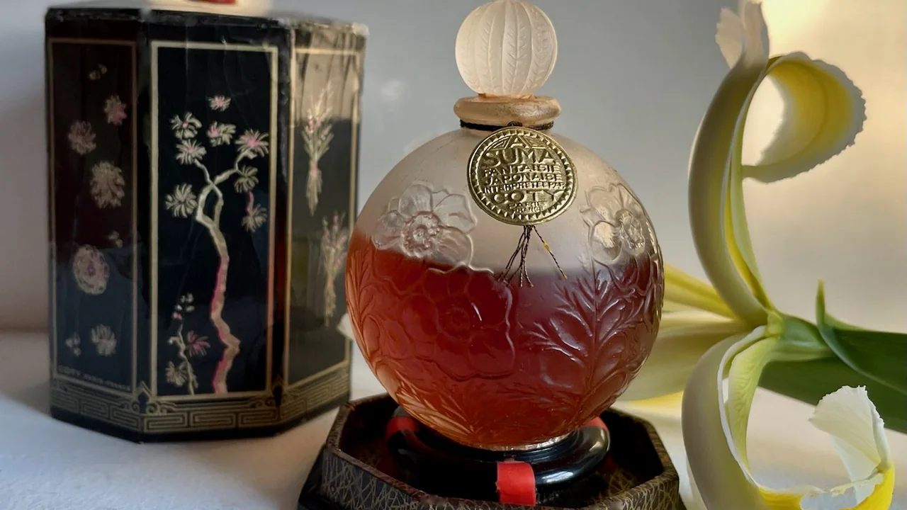 Garrafa vintage de perfume Suma ao lado da caixa decorada e de uma flor