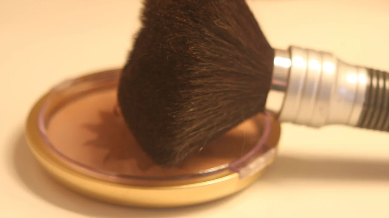 Pincel cosmético sobre uma embalagem de maquiagem; ferramenta opcional para aplicar primer.