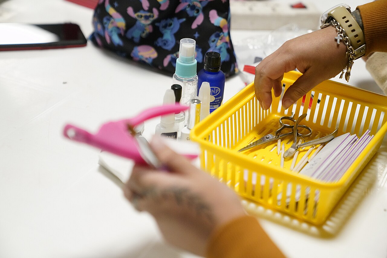 Cesta com alicates, lixas, palitos e frascos usados em uma prática de manicure