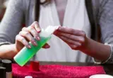 Mãos seguram algodão e frasco de removedor durante a preparação para remover esmalte em gel