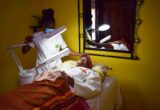 Profissional realizando atendimento facial com lupa e iluminação sobre cliente