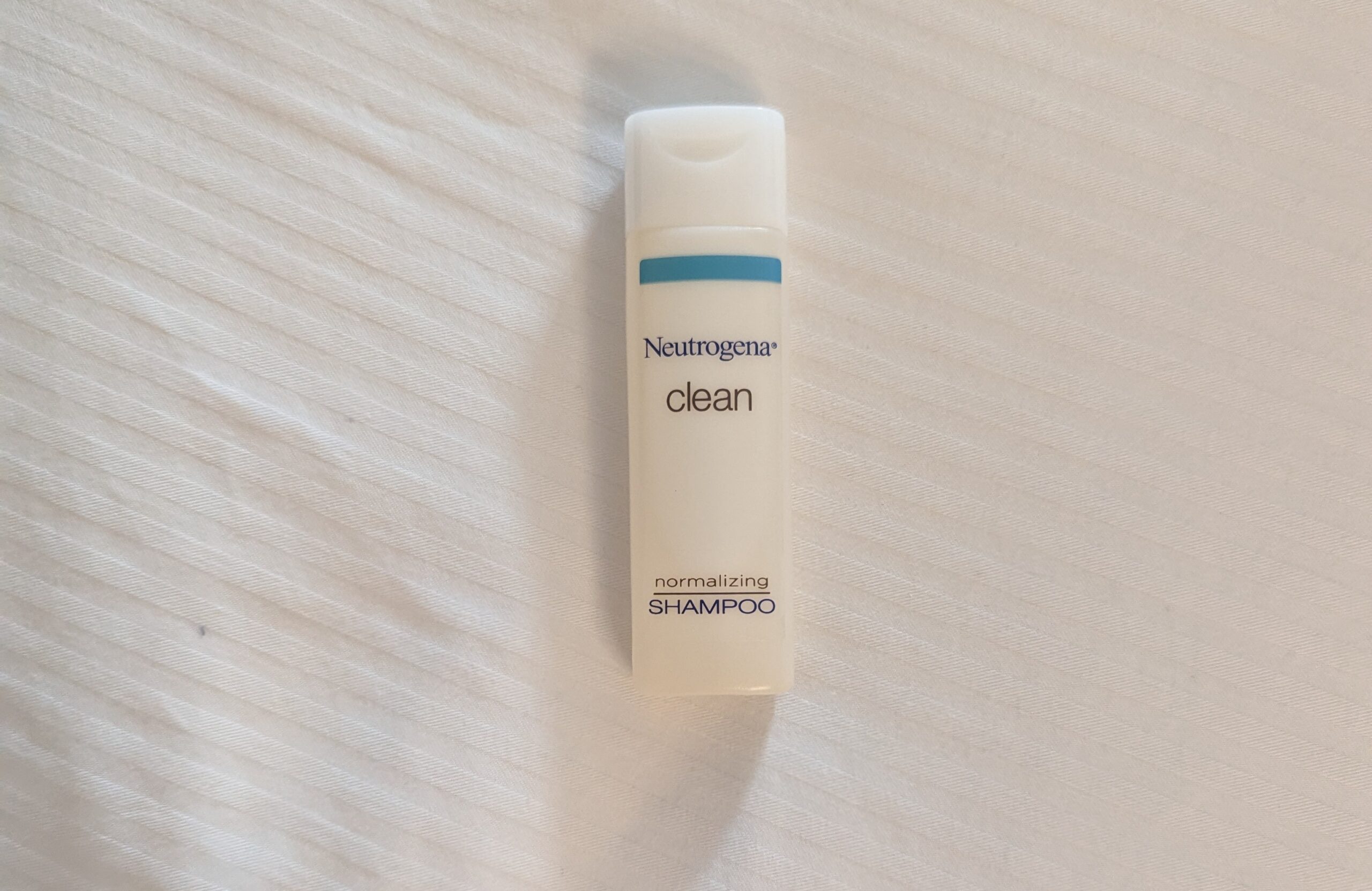 Frasco de shampoo Neutrogena Clean fotografado sobre tecido branco