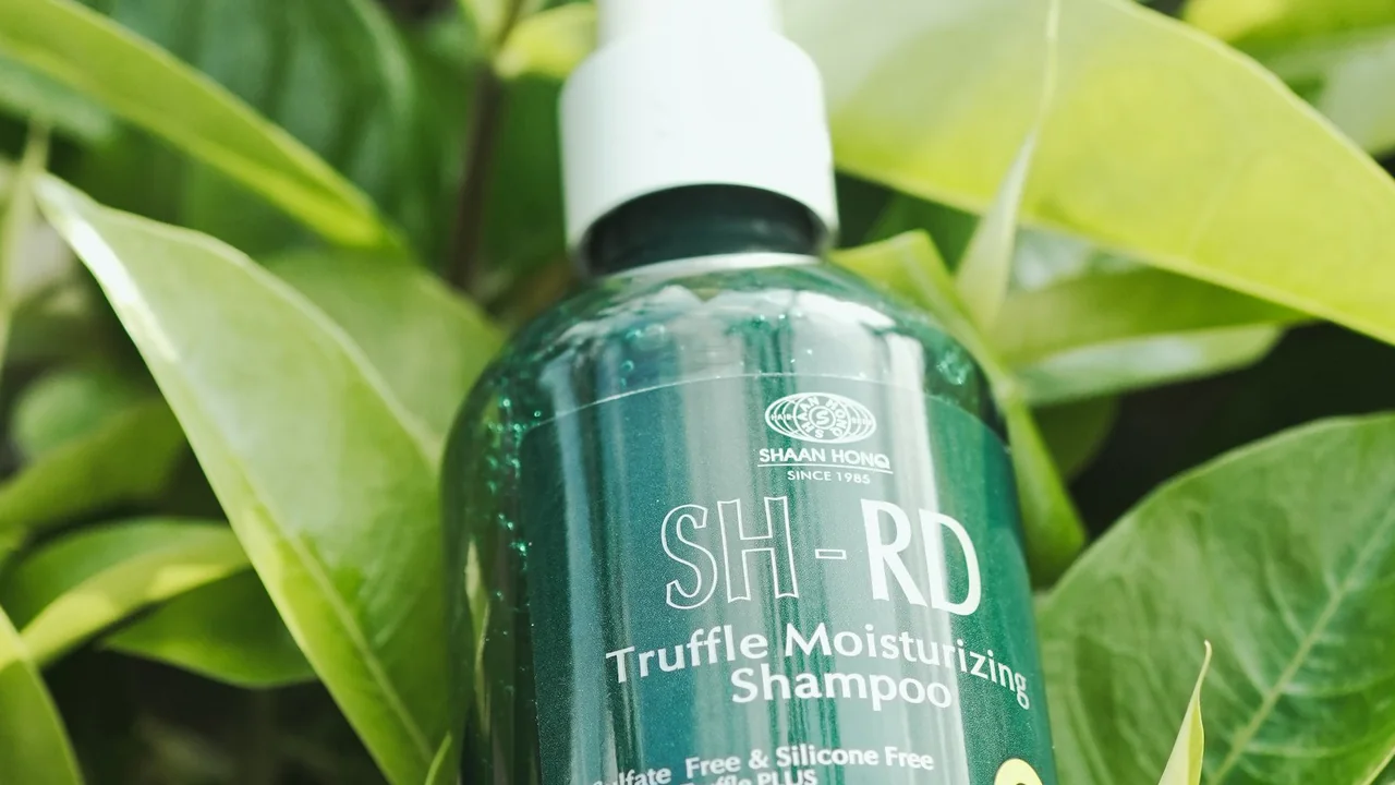 Frasco de shampoo hidratante entre folhas verdes, imagem ilustrativa para explicar a escolha de shampoo após progressiva
