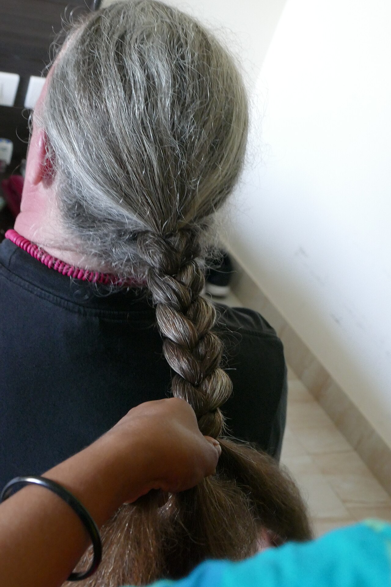 Mãos trabalhando na divisão e trançado de cabelos durante um atendimento