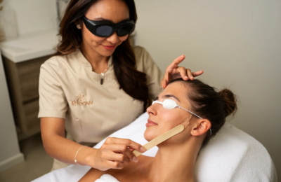 Profissional realiza procedimento facial em cliente sobre maca de estética.